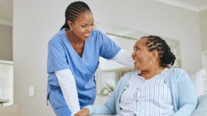 Healthcare worker supporting an older woman at home